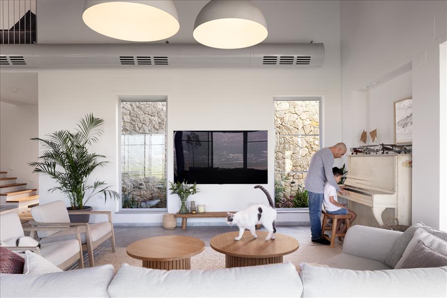 הסלון מוקף חלונות גדולים המכניסים את החוץ אל תוך העיצוב