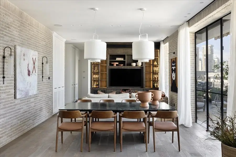 שולחן גדול וכיסאות עץ מרופדים היוצרים סביבם סצנה מזמינה של אירוח