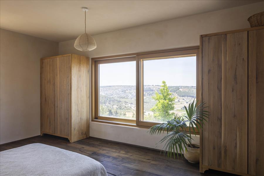 מול המיטה נפתח חלון רחב אל הנוף הגלילי